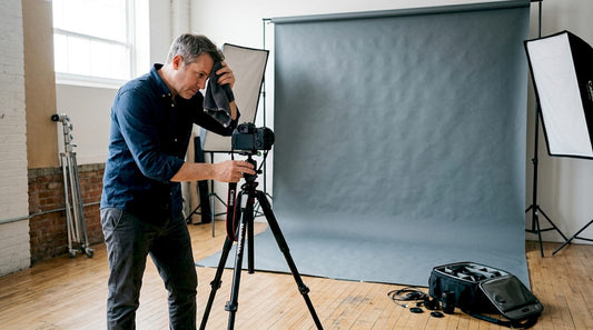 Photographer adjusting camera with large studio backdrop